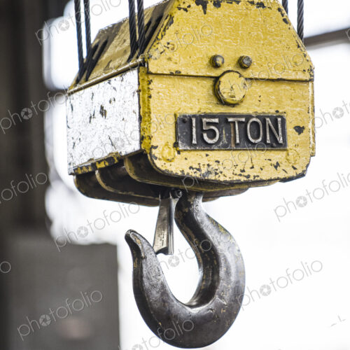 Closeup of a the hook on a heavy duty overhead lift in a sheet metal factory.