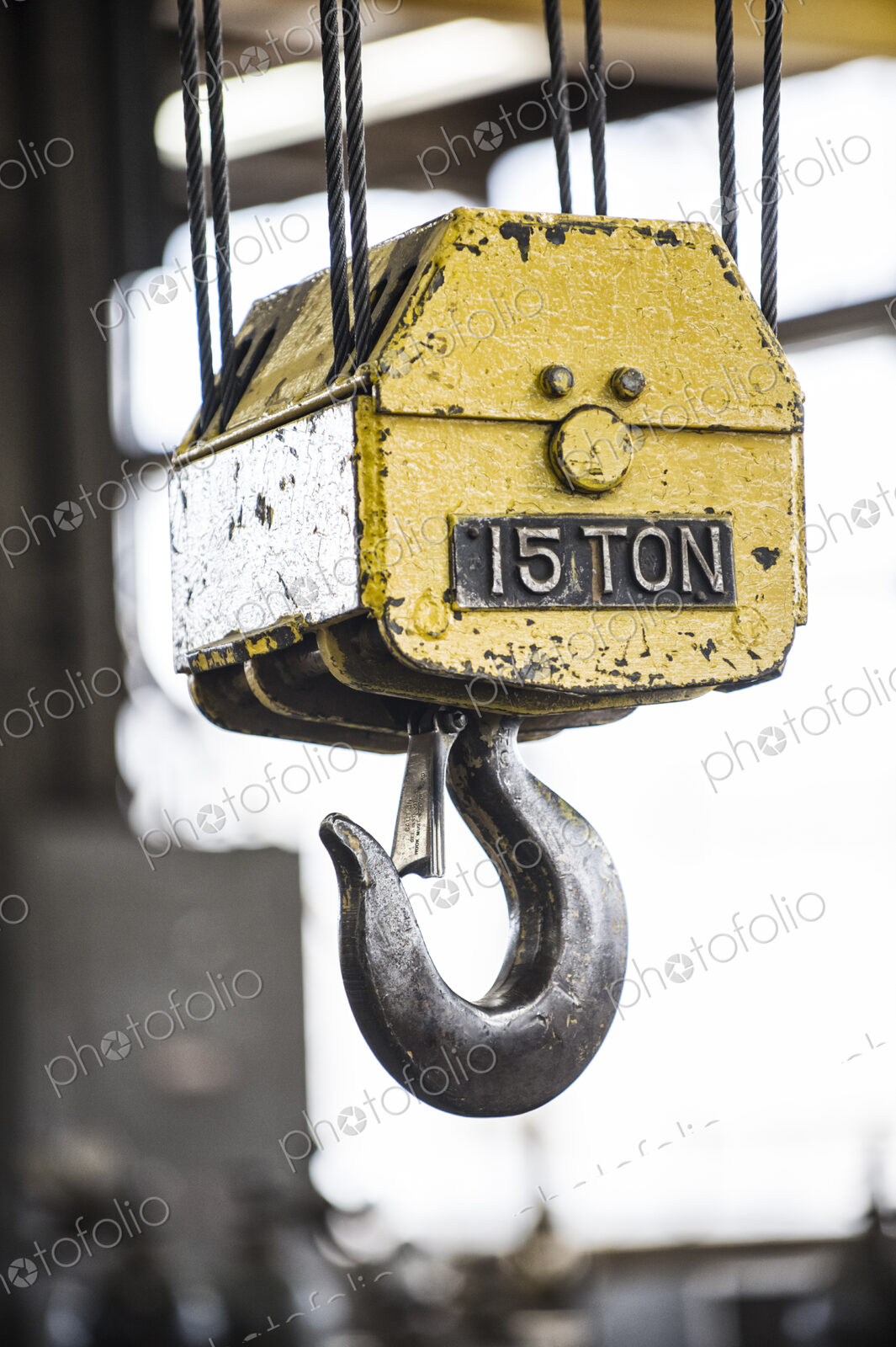 Closeup of a the hook on a heavy duty overhead lift in a sheet metal factory.