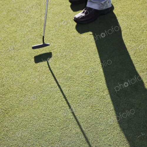 Closeup of golfer hitting a put and a golf ball going into the cup Closeup of golfer hitting a put and a golf ball going into the cup