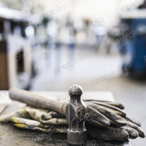 Closeup still life of gloves and a heavy duty hammer in a sheet metal factory. Closeup still life of gloves and a heavy duty hammer in a sheet metal factory.