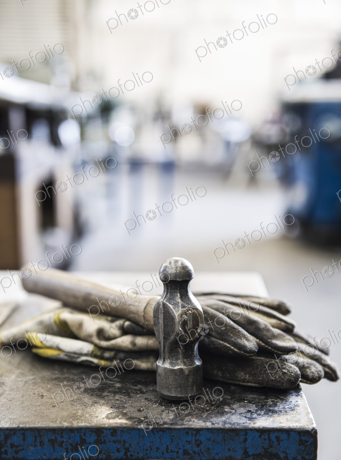 Closeup still life of gloves and a heavy duty hammer in a sheet metal factory.