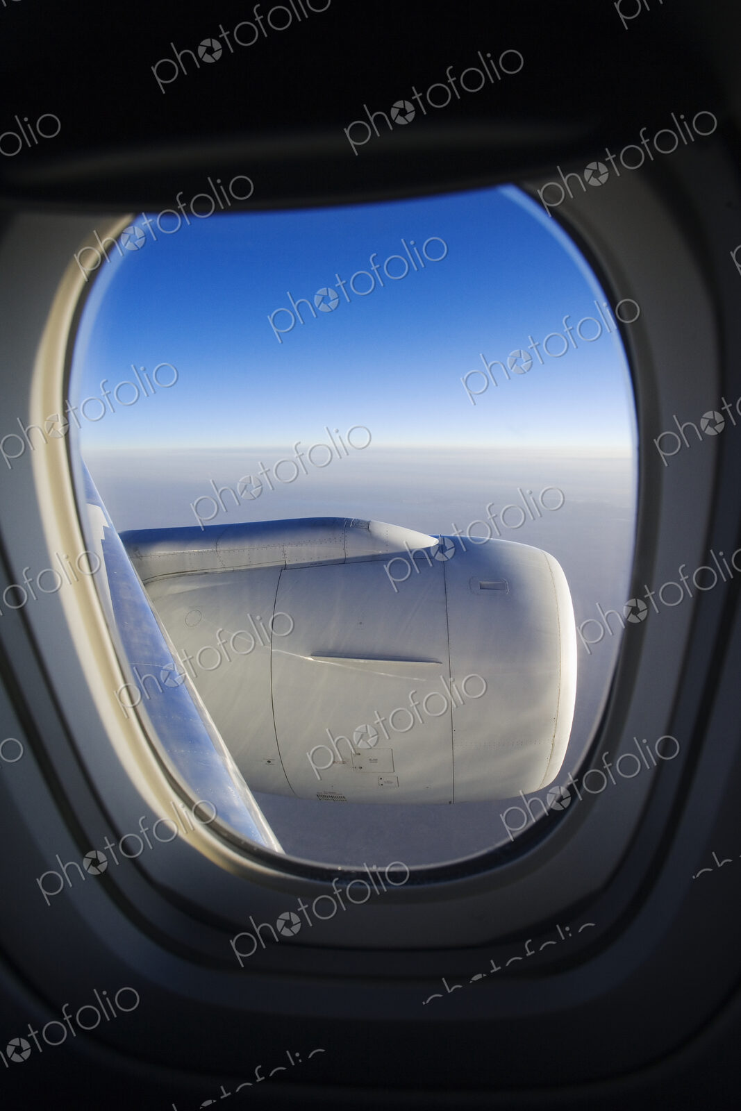 Cloud horizon with engine seen through airplane window.