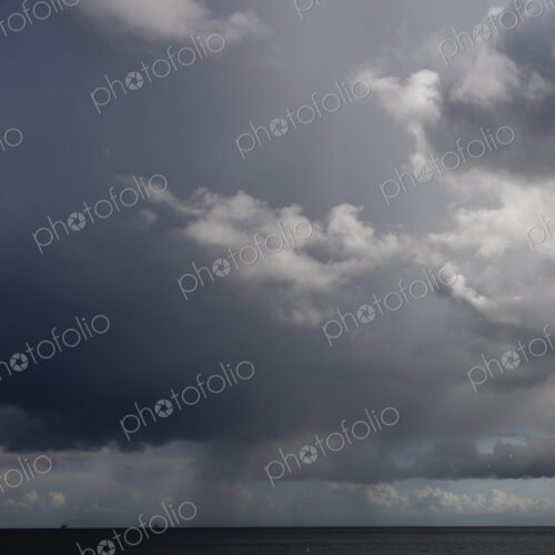 Cloudy dark sky above flat rural landscape.