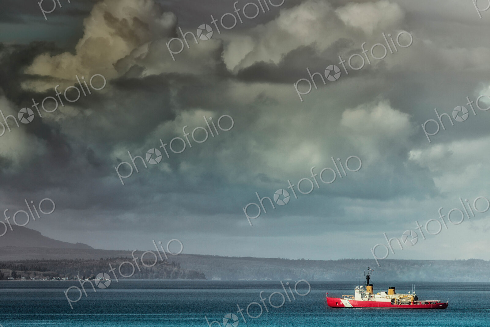 Coastguard boat sailing along coastline under moody sky.