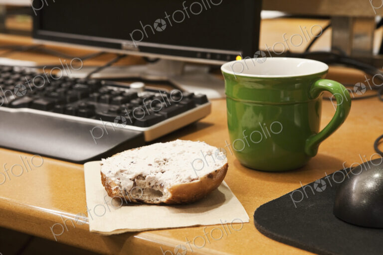 Coffee Cup and Bagel on a Desk