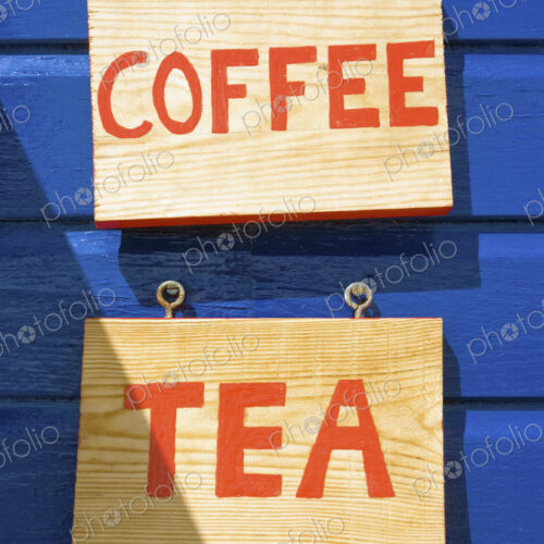 Coffee and tea signs on wooden wall or building exterior.