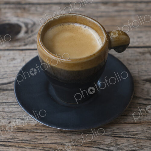 Coffee in espresso cup and saucer on wooden table Coffee in espresso cup and saucer on wooden table