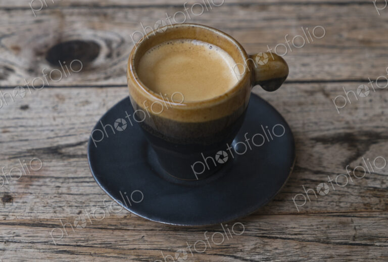Coffee in espresso cup and saucer on wooden table