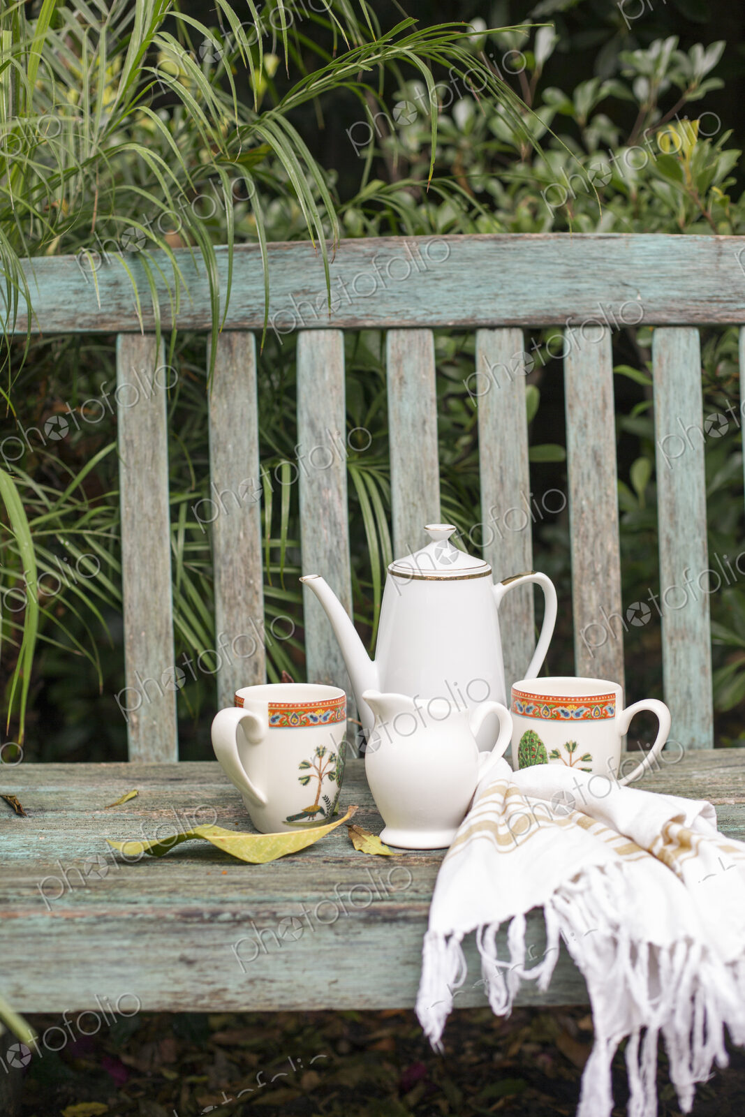 Coffee pot and mugs on a wooden garden bench.