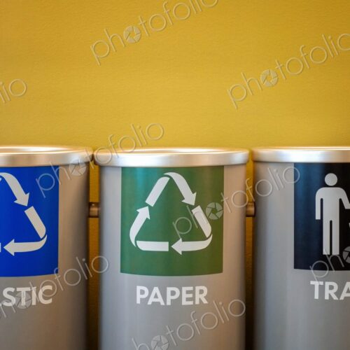 Color-coded bins for plastic recycling, paper recycling, and general trash disposal -…