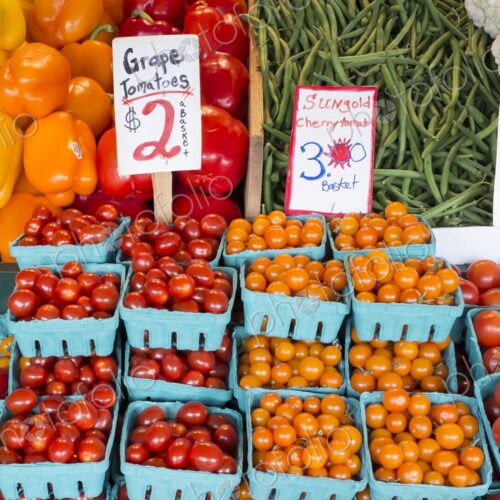 Colorful baskets of grape and cherry tomatoes displayed for sale alongside peppers,… Colorful baskets of grape and cherry tomatoes displayed for sale alongside peppers,…
