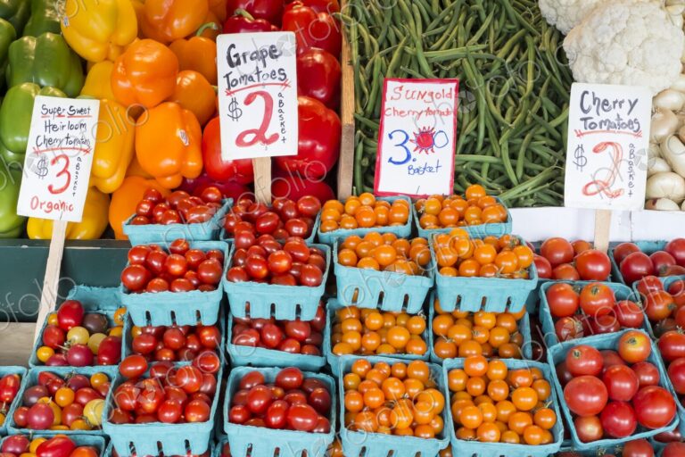Colorful baskets of grape and cherry tomatoes displayed for sale alongside peppers,…