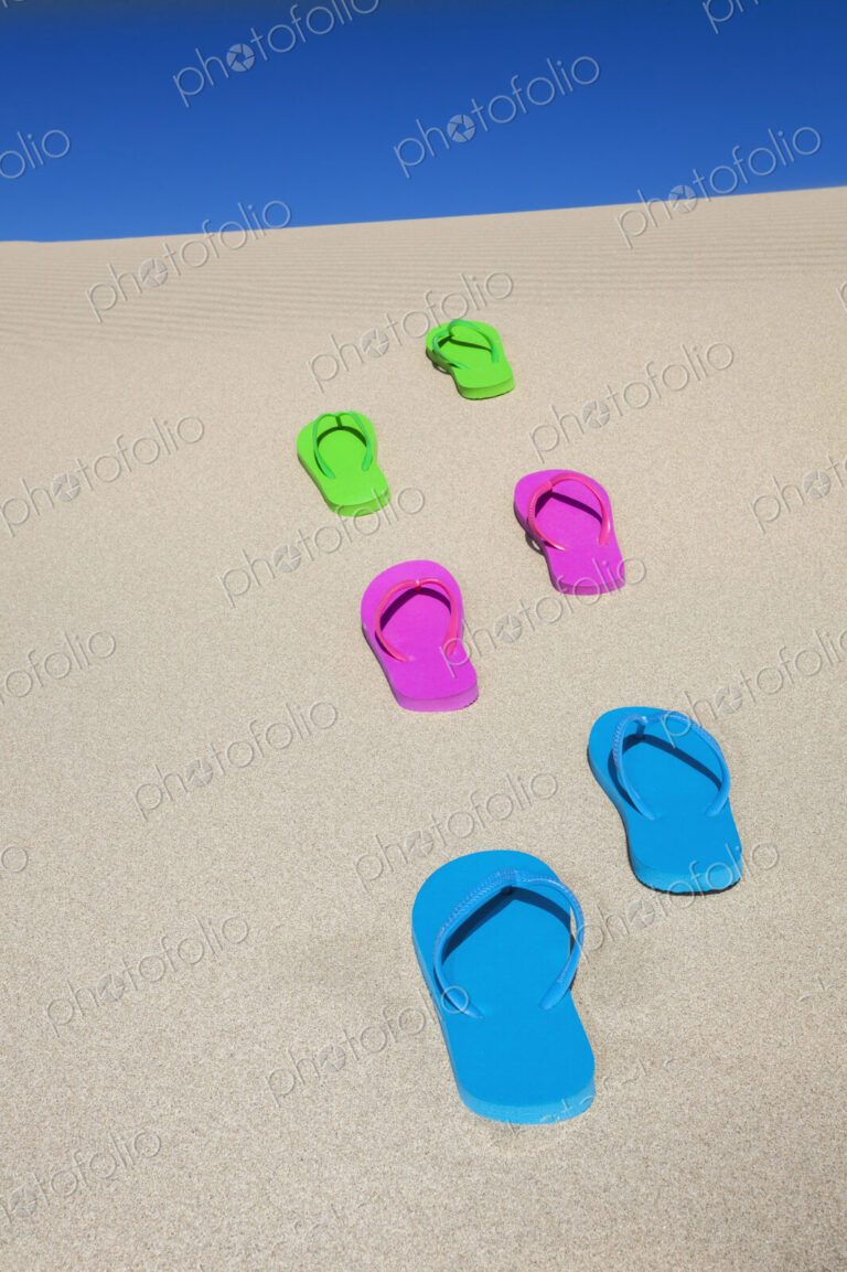 Colorful flip flops on sand