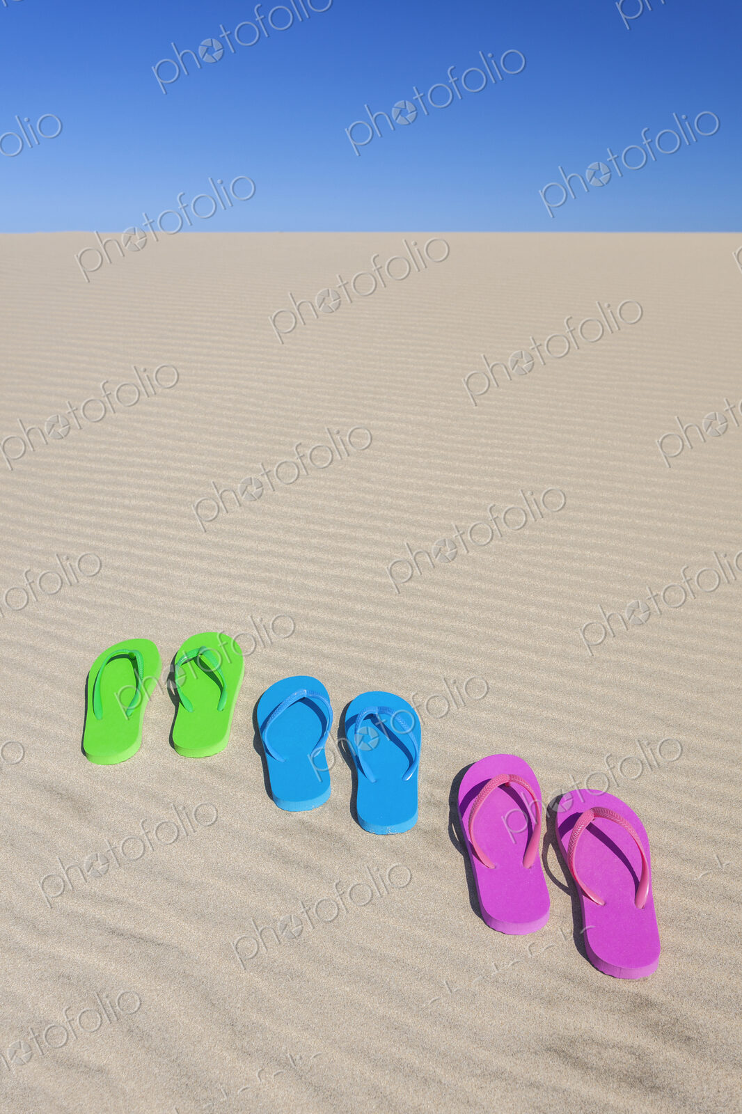 Colorful flip flops on sand dune