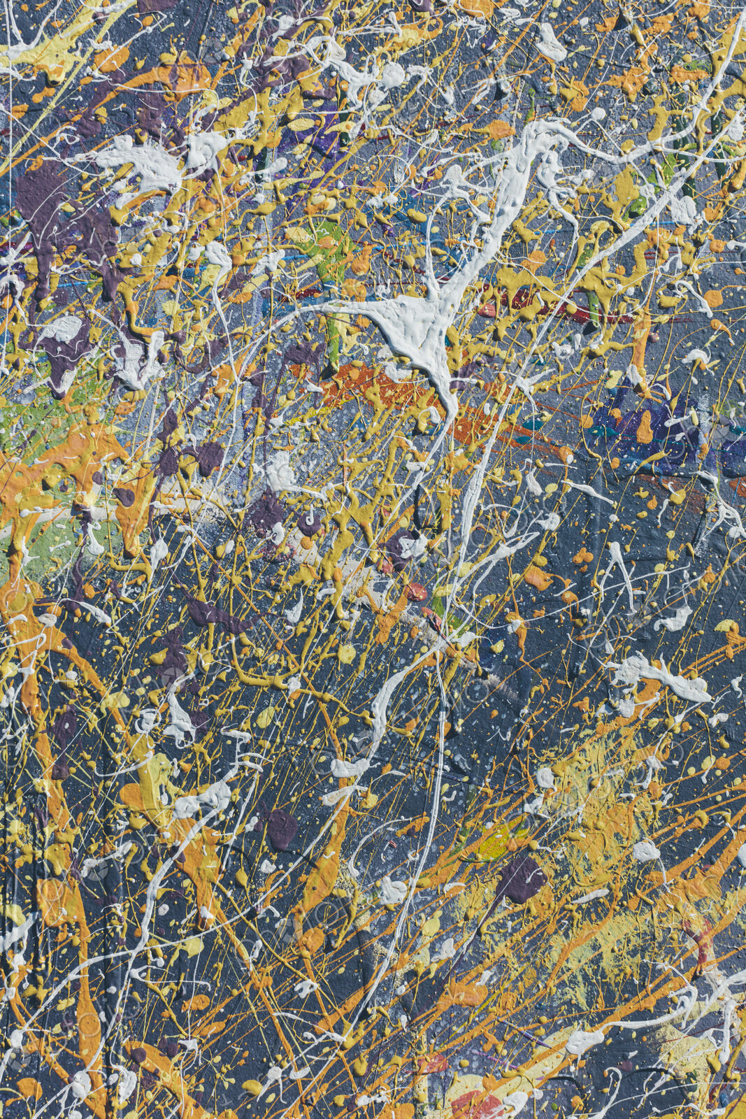 Colorful graffiti paint splattered and dripping on urban wall, close up