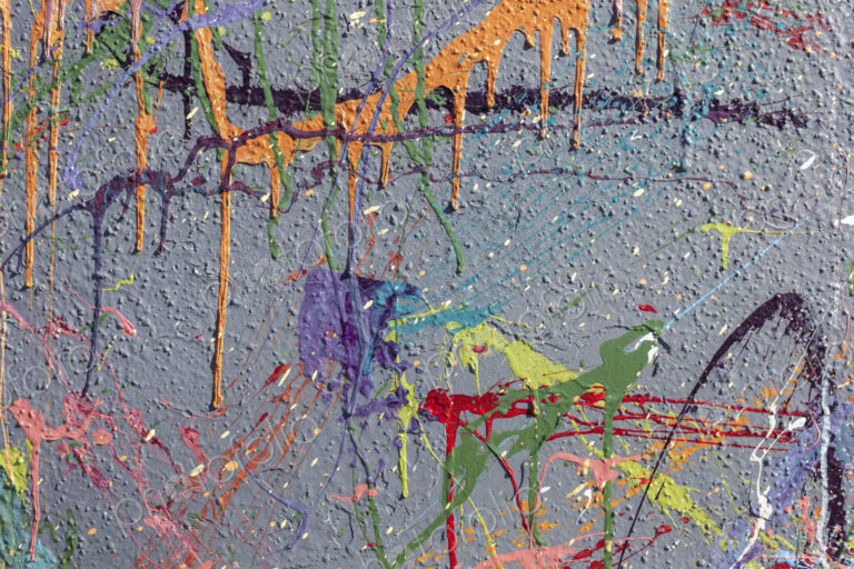 Colorful graffiti paint splattered and dripping on urban wall, close up