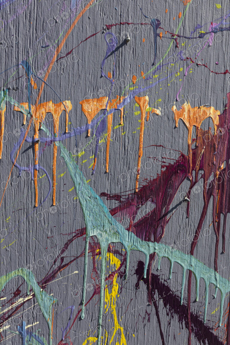 Colorful graffiti paint splattered and dripping on urban wall, close up