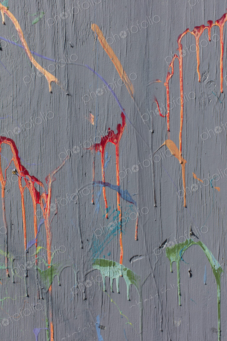Colorful graffiti paint splattered and dripping on urban wall, close up