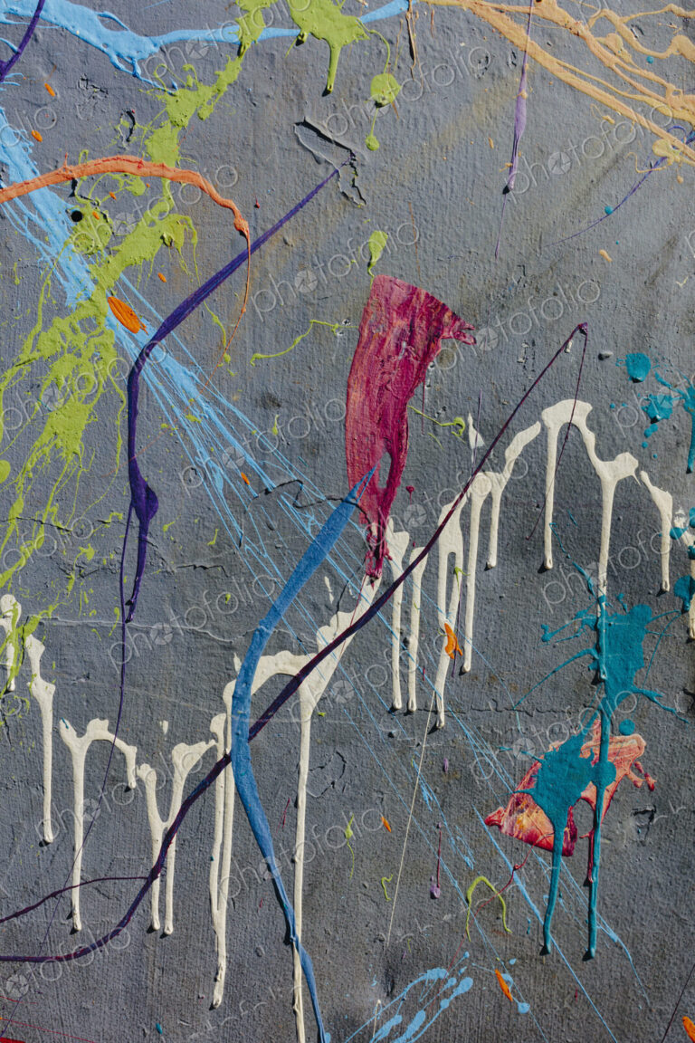 Colorful graffiti paint splattered and dripping on urban wall, close up