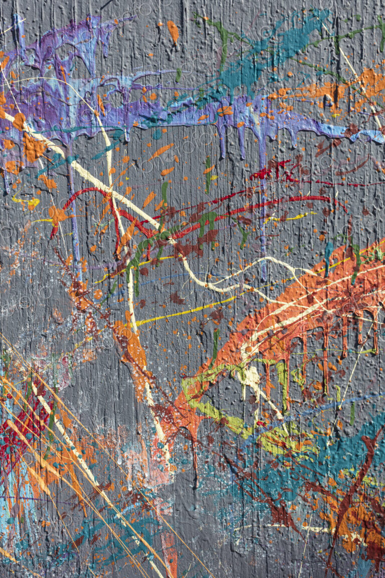Colorful graffiti paint splattered and dripping on urban wall, close up