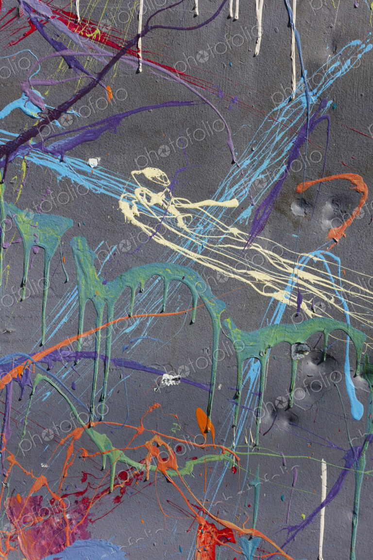 Colorful graffiti paint splattered and dripping on urban wall, close up