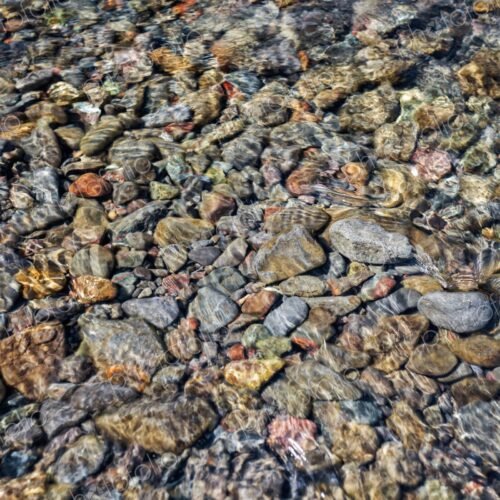 Colorful stones visible through clear shallow water along the shoreline of Lake… Colorful stones visible through clear shallow water along the shoreline of Lake…