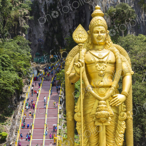 Colossal golden statue of Hindu deity, with stairway into cave in the background. Colossal golden statue of Hindu deity, with stairway into cave in the background.