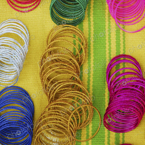 Coloured bangles paid out on a yellow and green striped background. Coloured bangles paid out on a yellow and green striped background.