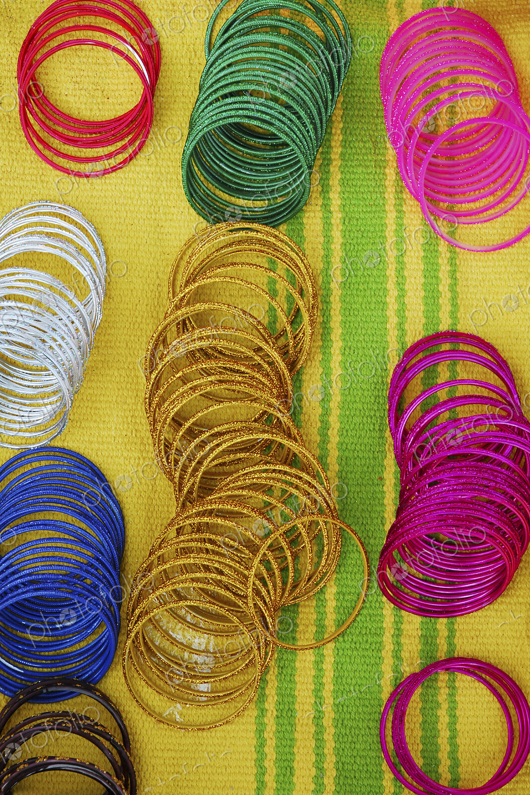 Coloured bangles paid out on a yellow and green striped background.