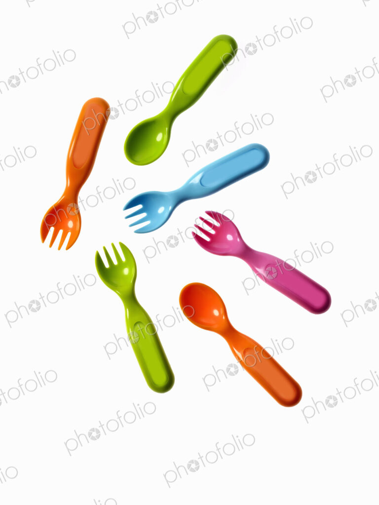 Colourful plastic spoons and forks, for use by infants and babies.