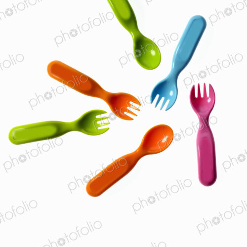 Colourful plastic spoons and forks, for use by infants and babies.