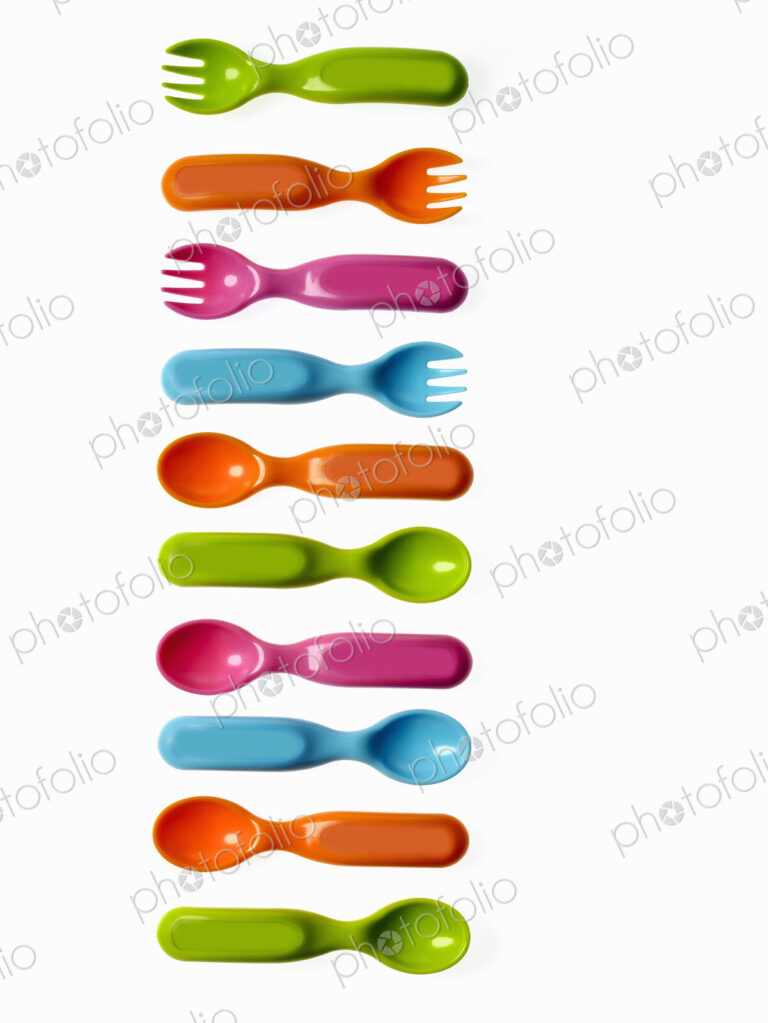 Colourful plastic spoons and forks, for use by infants and babies.