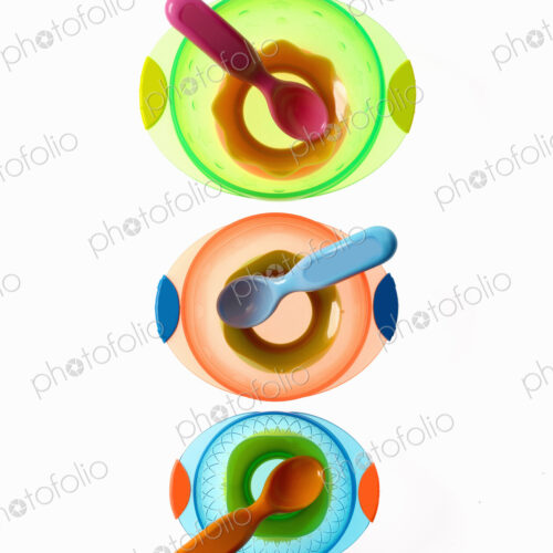 Colourful plastic spoons for use by infants and babies. Coloured plastic bowls.