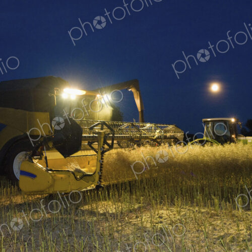 Combine harvester and grain trailer working at night under lights. Combine harvester and grain trailer working at night under lights.