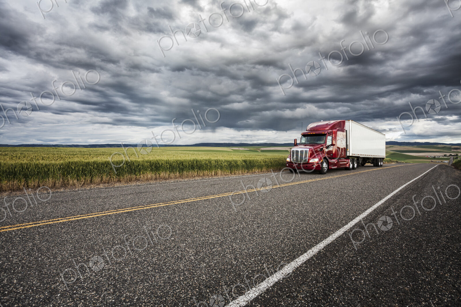 Commercial truck driving though wheat fields of eastern Washington, USA at sunset.