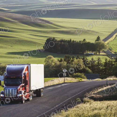Commercial truck driving though wheat fields of eastern Washington, USA at sunset.