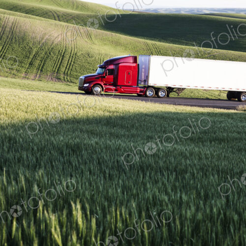 Commercial truck driving though wheat fields of eastern Washington, USA at sunset.