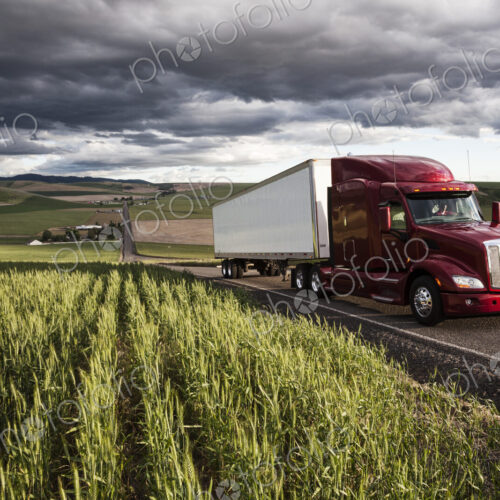 Commercial truck driving though wheat fields of eastern Washington, USA at sunset.