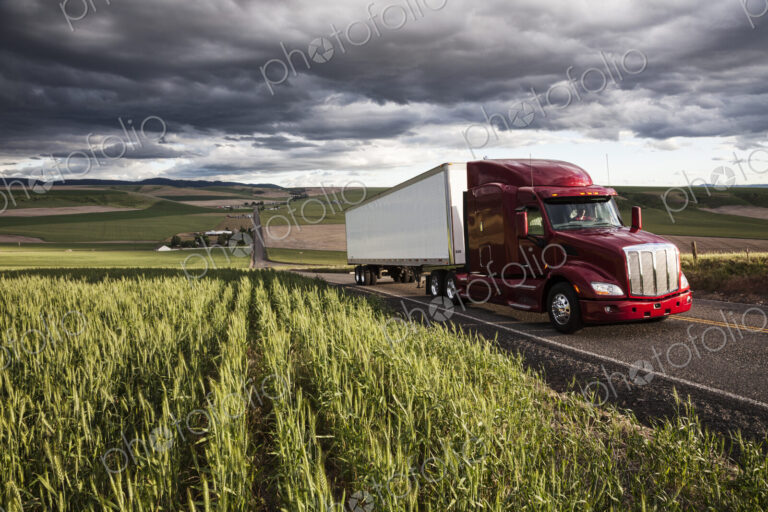 Commercial truck driving though wheat fields of eastern Washington, USA at sunset.