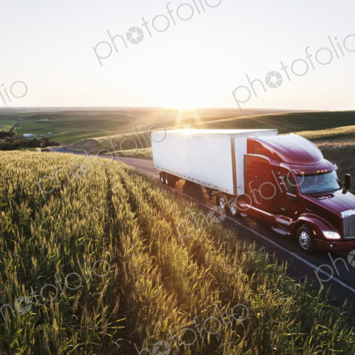 Commercial truck driving though wheat fields of eastern Washington, USA at sunset.