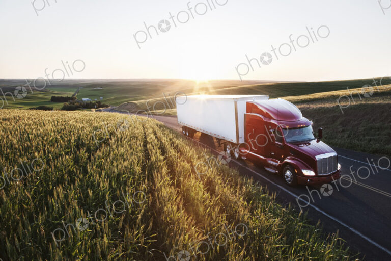 Commercial truck driving though wheat fields of eastern Washington, USA at sunset.