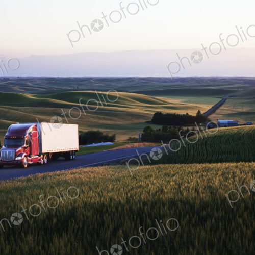 Commercial truck driving though wheat fields of eastern Washington, USA at sunset.