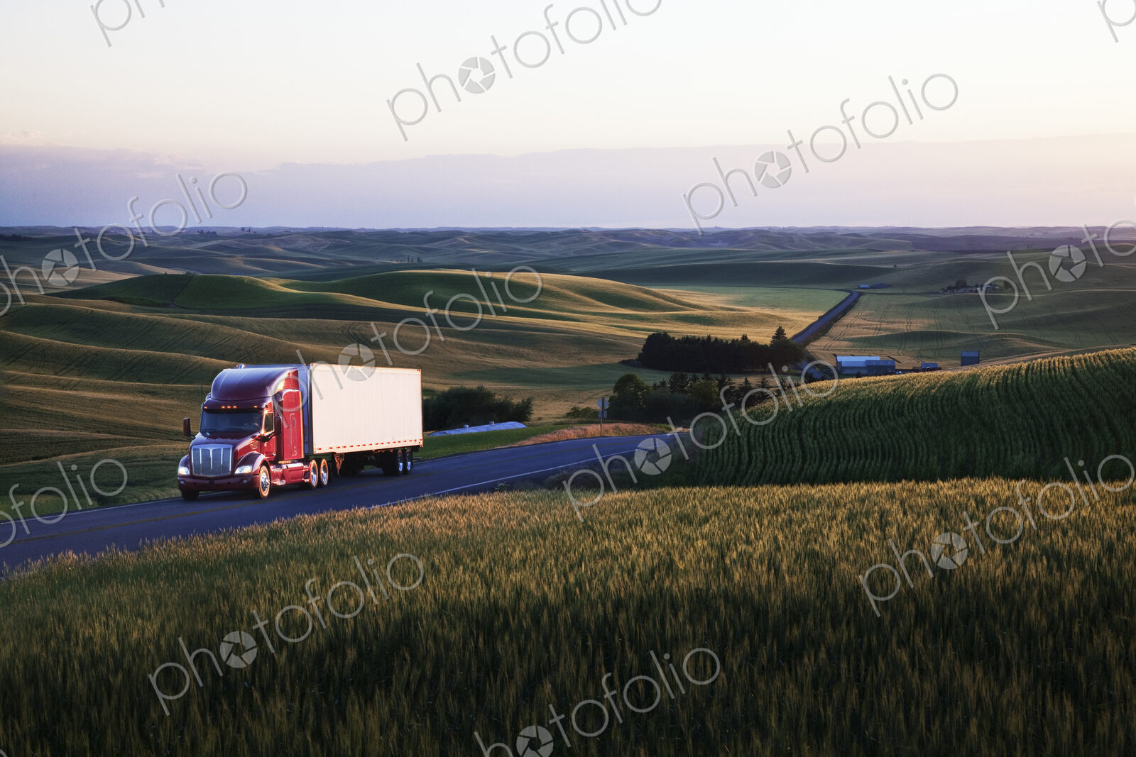 Commercial truck driving though wheat fields of eastern Washington, USA at sunset.