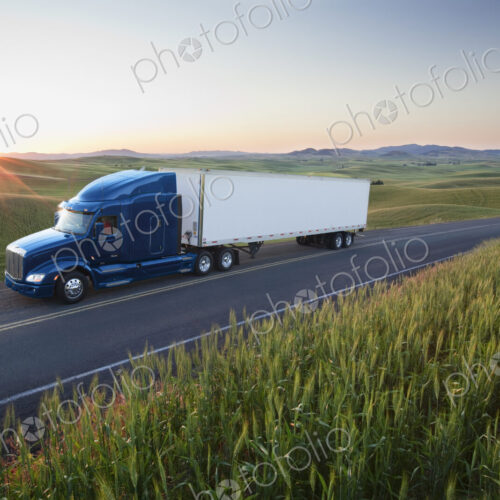 Commercial truck driving though wheat fields of eastern Washington, USA at sunset. Commercial truck driving though wheat fields of eastern Washington, USA at sunset.