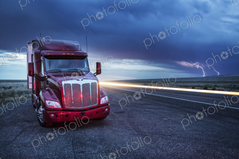 Commercial truck parked on the verge of rural road late in the day, lightning in the…