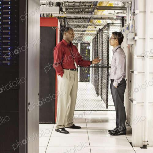 Computer technicians discussion an issue in a large computer server farm.