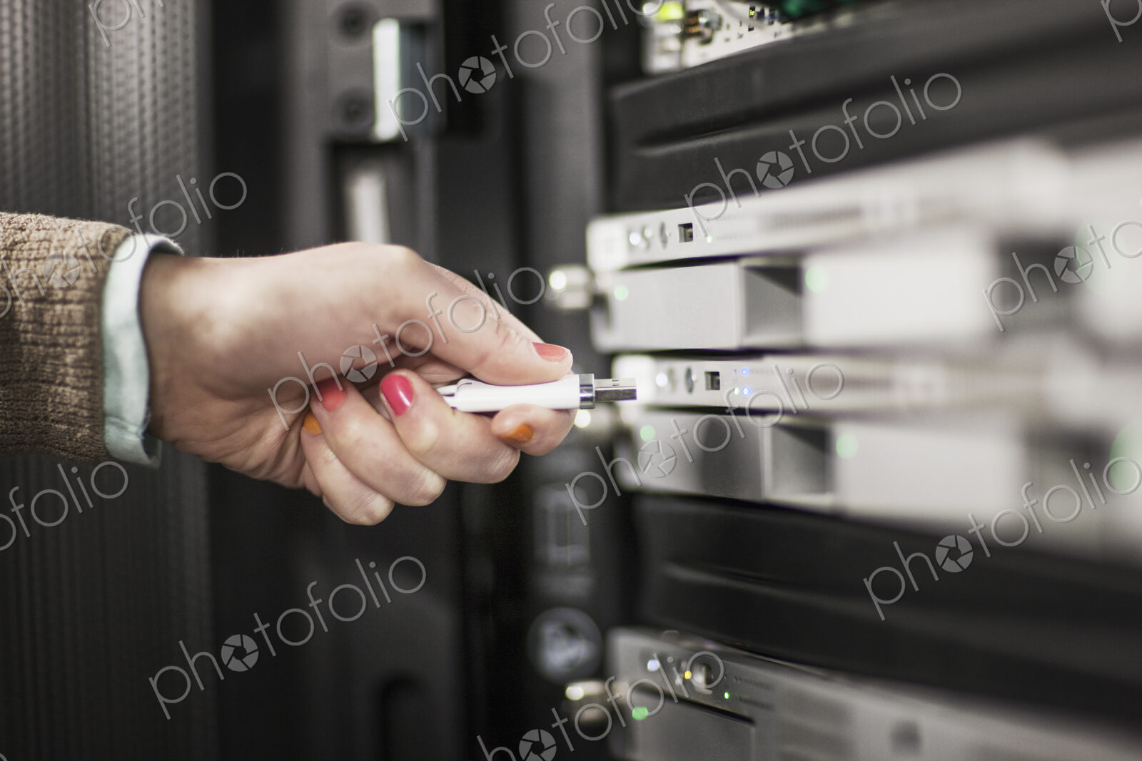Computer techniican inserting thumb drive into a server in a server farm.