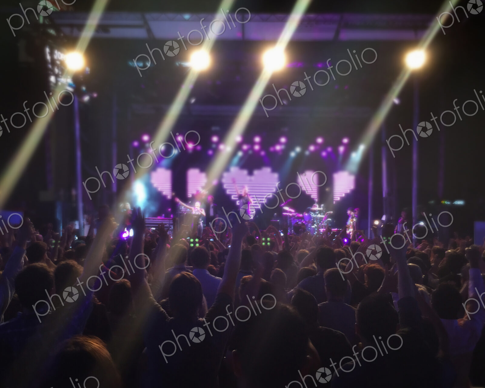Concert goers watching performers on stage at music festival.