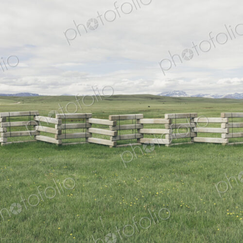 Concrete snow barrier and fencing across verdant mountain meadow Concrete snow barrier and fencing across verdant mountain meadow