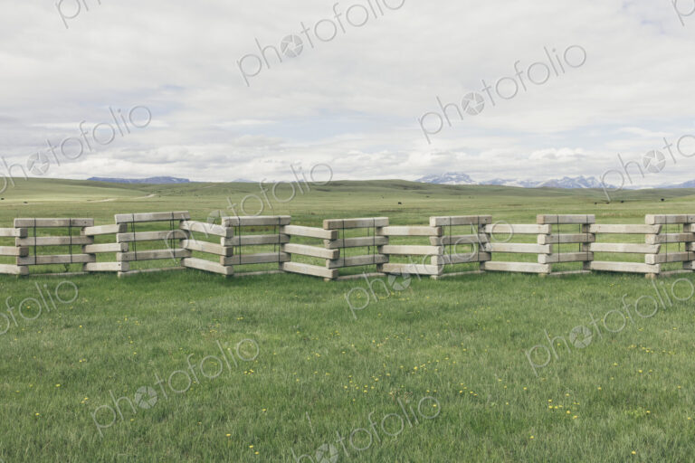 Concrete snow barrier and fencing across verdant mountain meadow